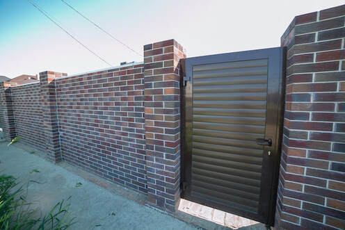 Solid decorative brick wall with a metal door way for access.
